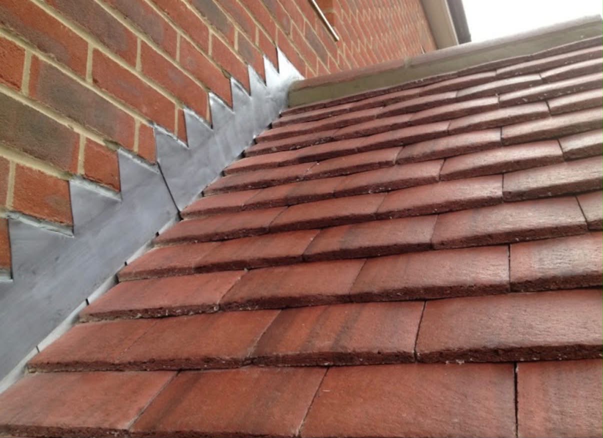 Stepped lead flashing where the tiles meet a brick wall